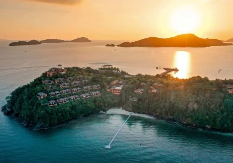 Bird's eye view of a island resort at sunset with islands in the backdrop.
