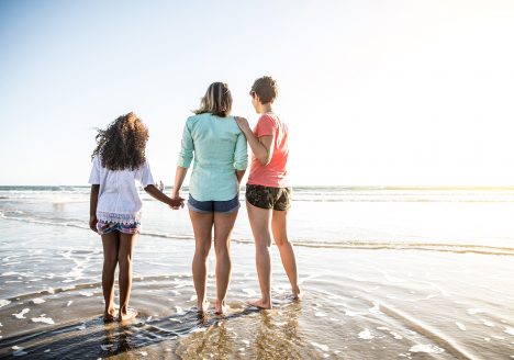 Lesbian mothers with daughter by the beach
