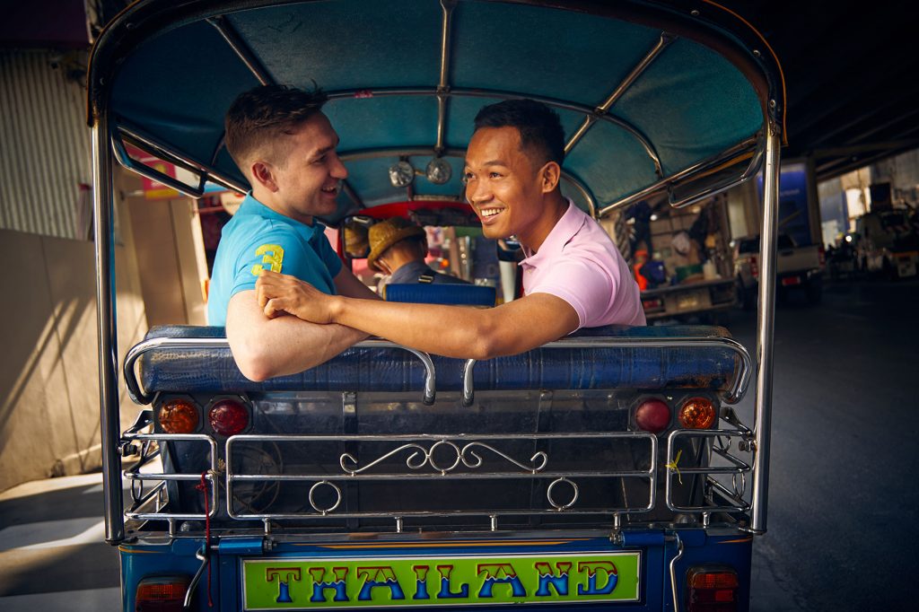 Gay couple enjoying a tuk tuk ride in Bangkok, Thailand