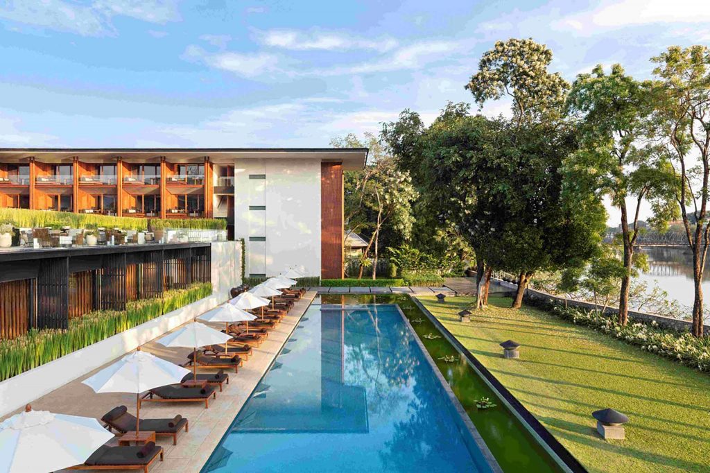 Large lap pool beside a green lawn and modern building.
