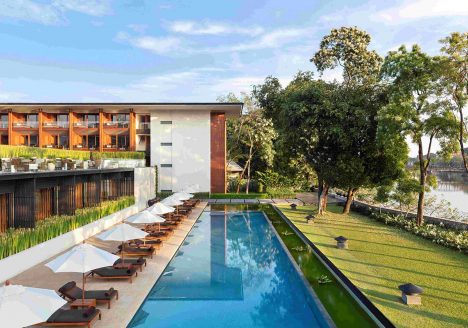 Large lap pool beside a green lawn and modern building.