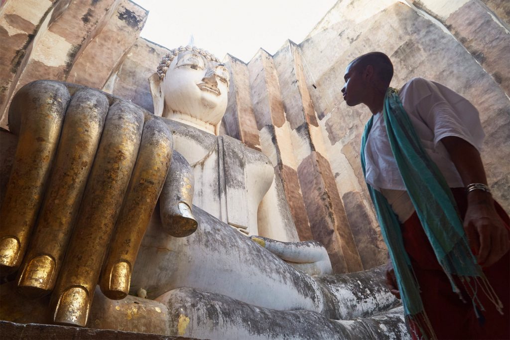 An LGBT+ traveller marvels at a Buddha statue in Sukhothai, Thailand