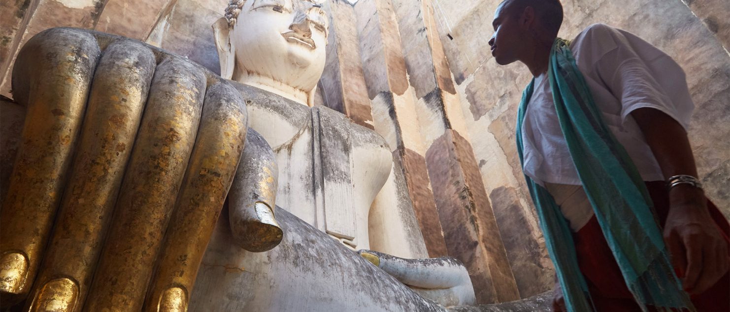 An LGBT+ traveller marvels at a Buddha statue in Sukhothai, Thailand