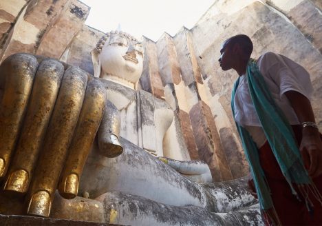 An LGBT+ traveller marvels at a Buddha statue in Sukhothai, Thailand