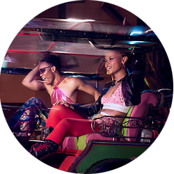 Two young people in clubwear ride on the back of a tuk-tuk in Thailand