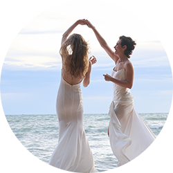 A newly-wed same gender female couple in bridal dresses, dance on the beach in Thailand