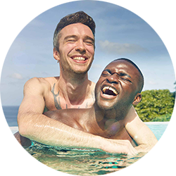 Two men, embrace and laugh in a pool in Thailand