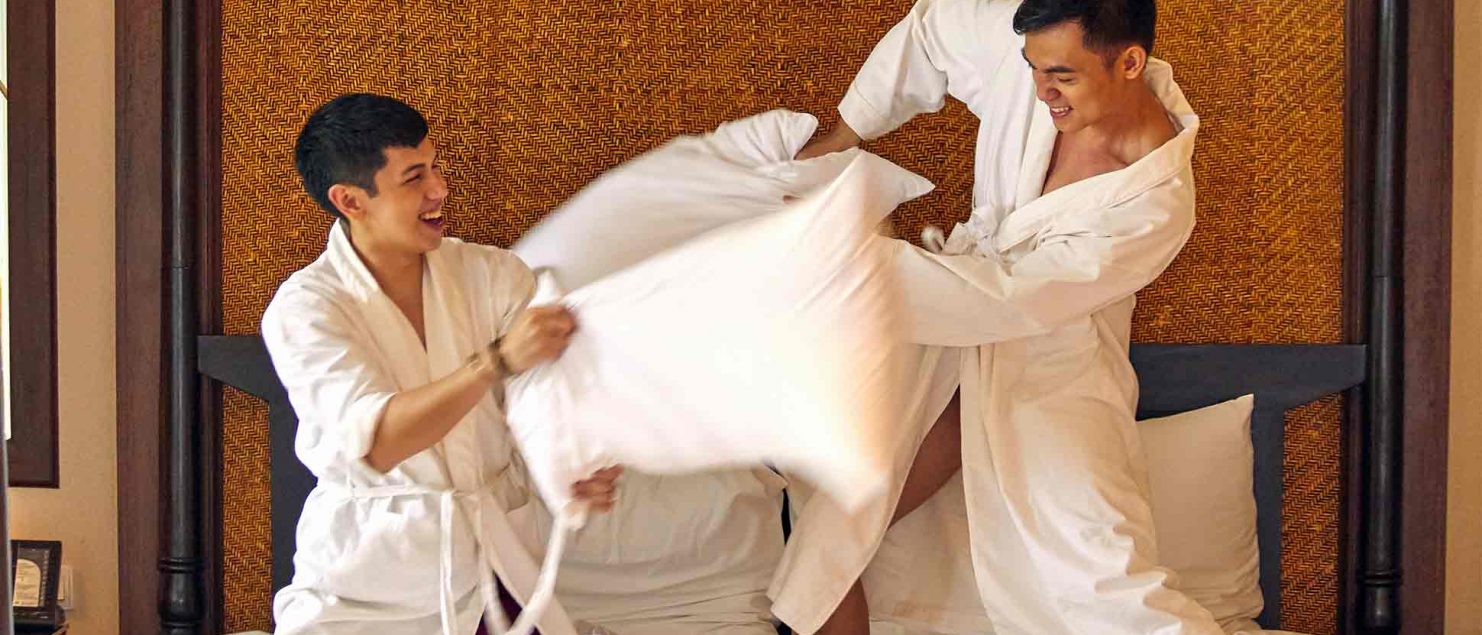 Same-sex couple during a pillow fight at one of the many Gay-friendly hotels in Thailand