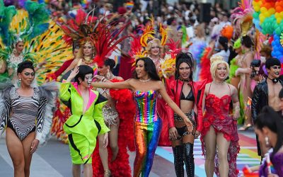A row of queer women walk the Bangkok parade in elaborate outfits
