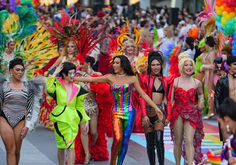 A row of queer women walk the Bangkok parade in elaborate outfits