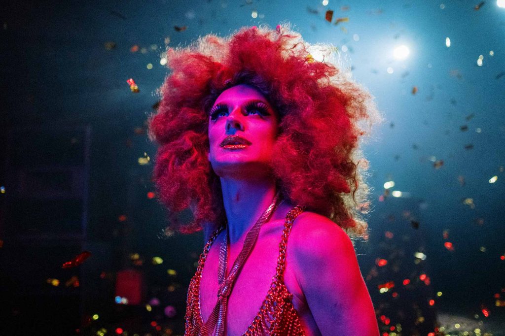 A drag queen soaks up the atmosphere at a show. Colourful confetti falls around her.