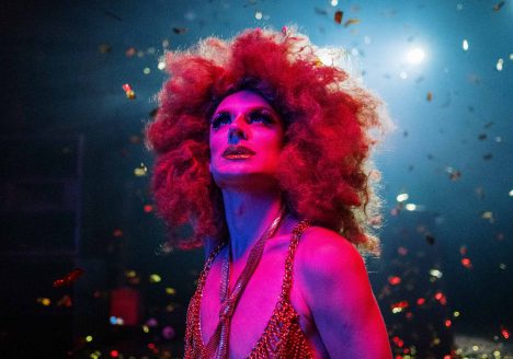 A drag queen soaks up the atmosphere at a show. Colourful confetti falls around her.