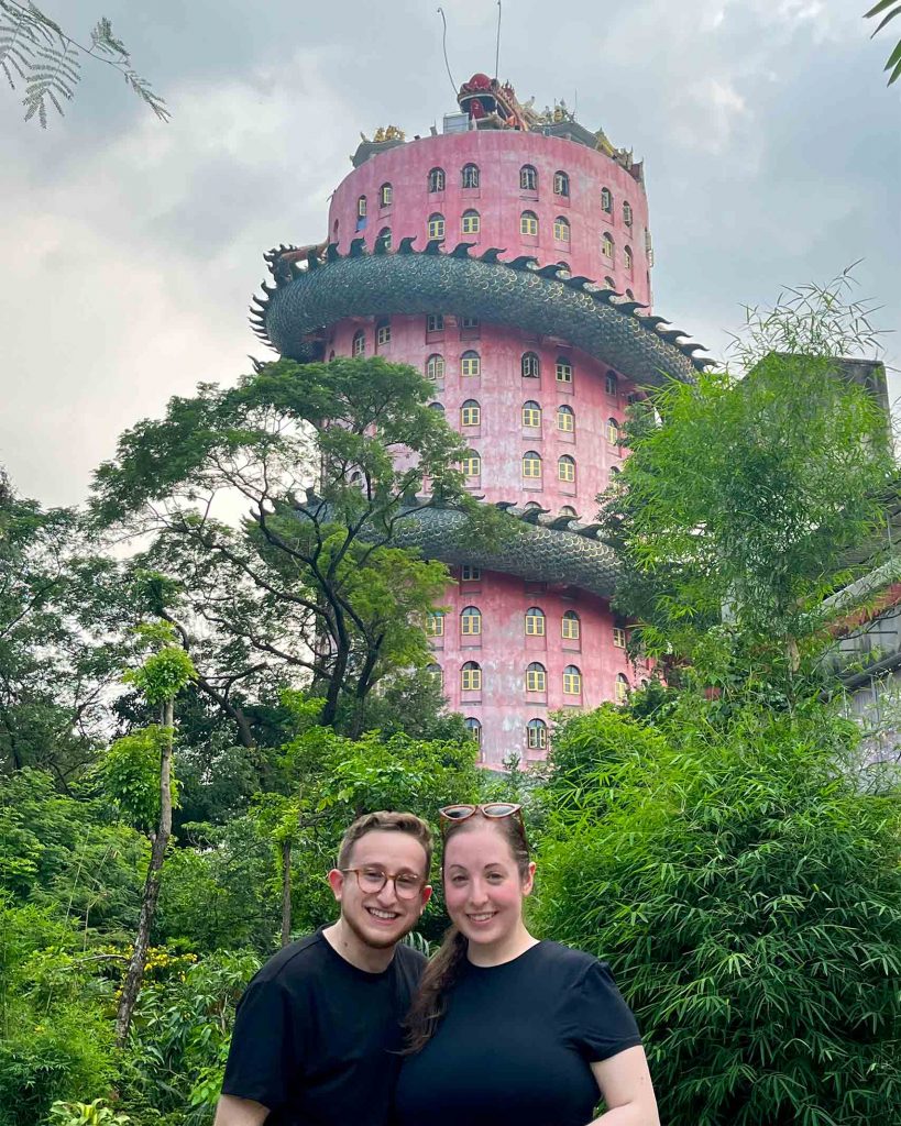 Queer couple Ilana and Ren outside of the uniquely shaped Wat Sam Phran temple in Khlong Mai, Thailand.