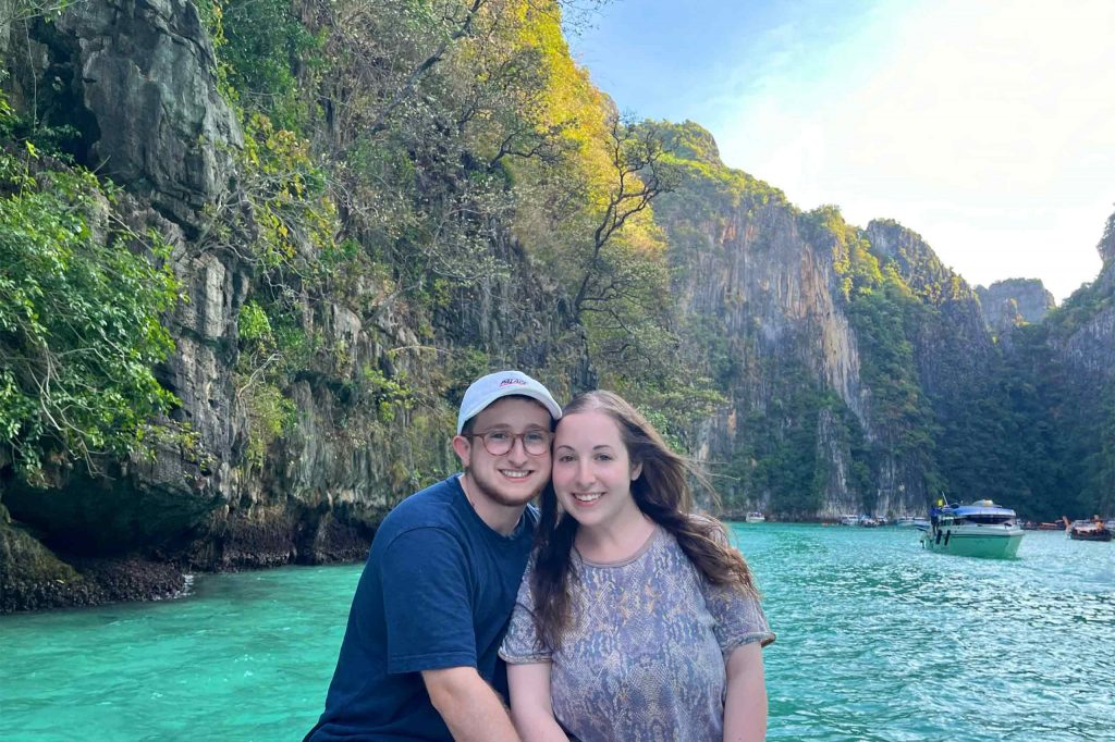 Iland and Ren explore the Phi Phi Islands with a limestone islet behind them. Visiting these islands is one of their favourite queer-friendly activities in Thailand. 