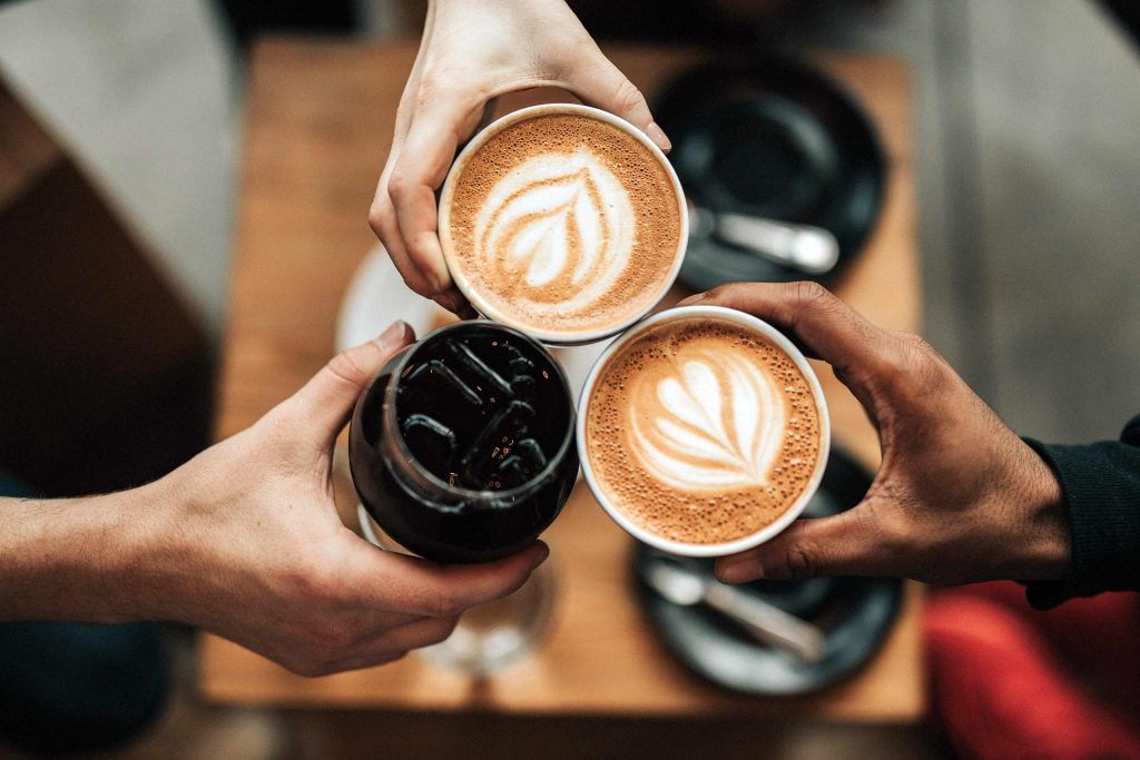 A group of friends cheers with cups of coffee in Chiang Mai, Thailand.