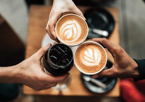 A group of friends cheers with cups of coffee in Chiang Mai, Thailand.