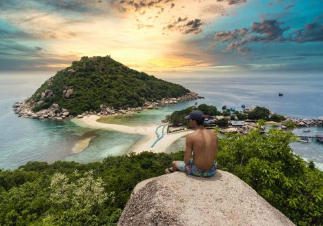 A traveller looking at an island from a viewpoint.
