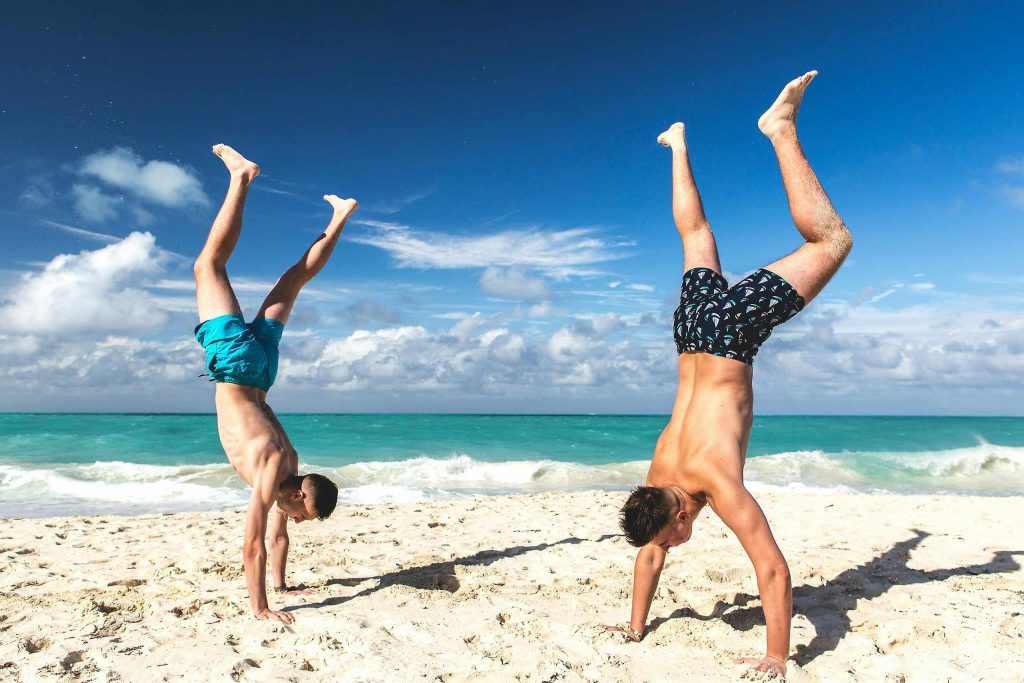 Two gay travellers doing handstands on a pristine beach in Koh Samet.