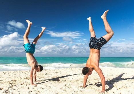 Two gay travellers doing handstands on a pristine beach in Koh Samet.