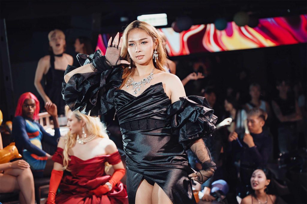 A ballroom performer in Bangkok. She's wearing a black dress and is surrounded by a cheering audience.