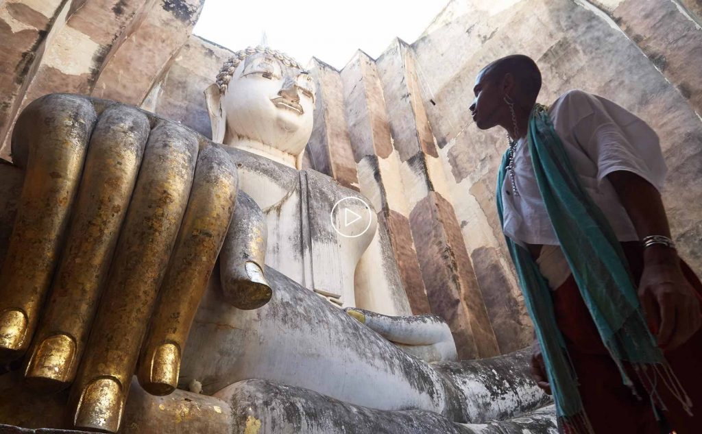 GTBF-Video-Thumbnails-new-2 A non-binary black person stands in the majesty of a large buddha effigy in Sukothai, Thailand