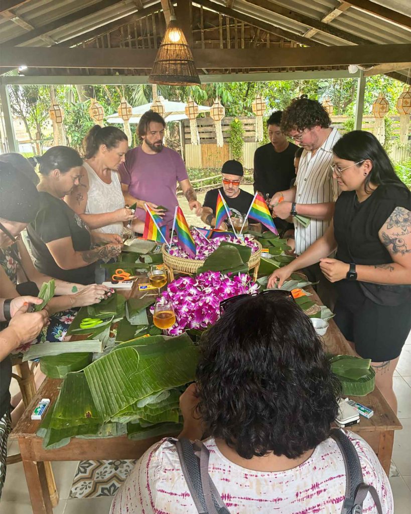 A group of travellers surrounding a table, making handicrafts using leaves.