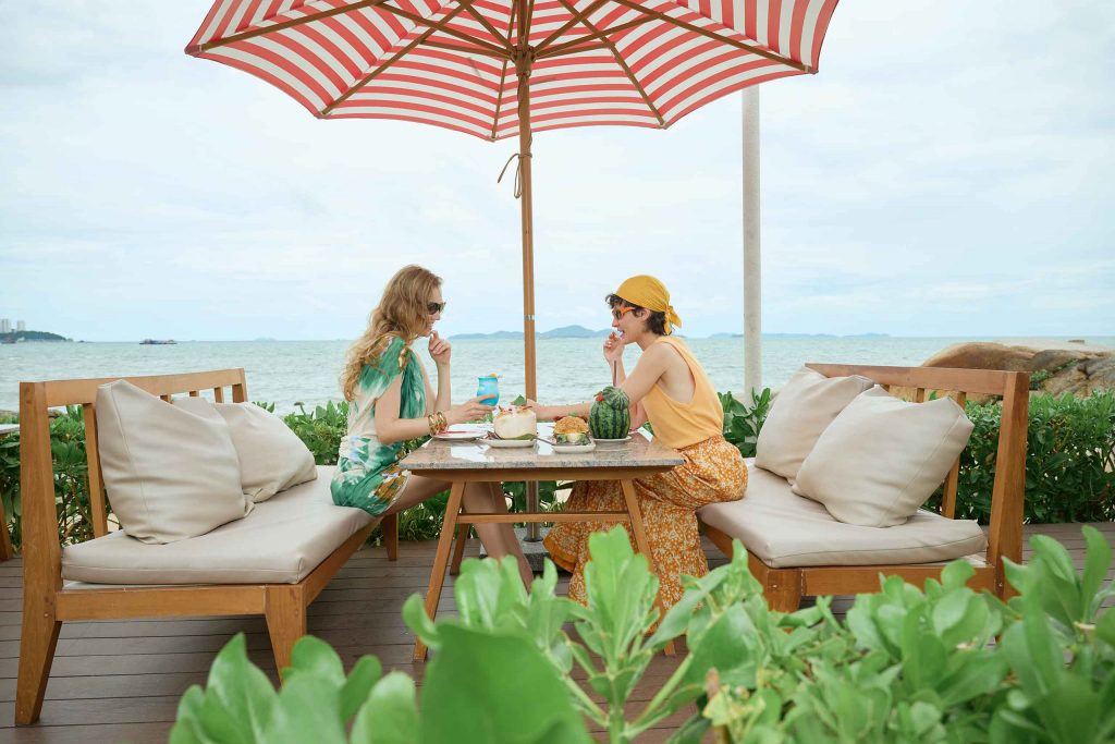 Two women sit and have breakfast by the sea