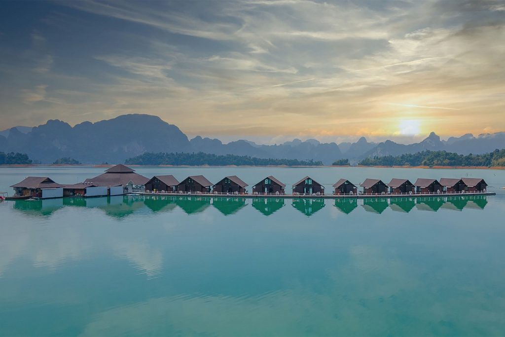 Floating lodges lined up on a large lake at sunset.