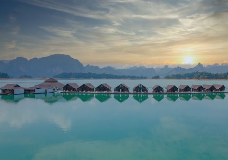 Floating lodges lined up on a large lake at sunset.