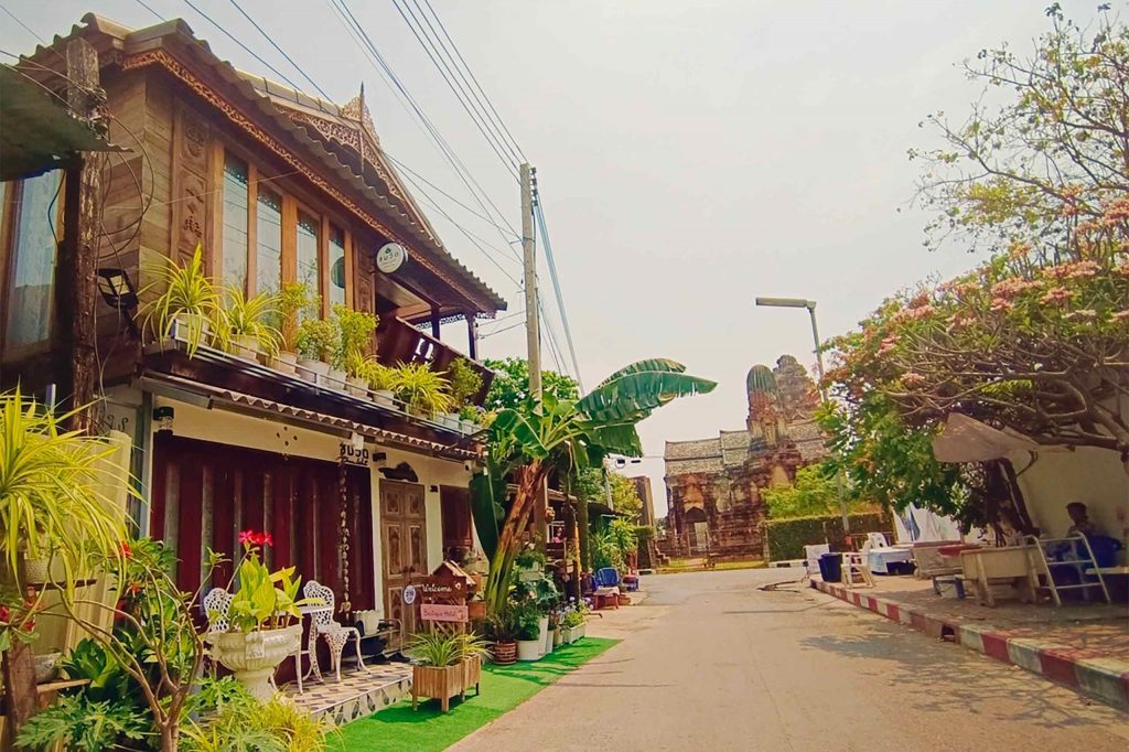 A charming boutique hotel surrounded by plants on a quaint Thai street.