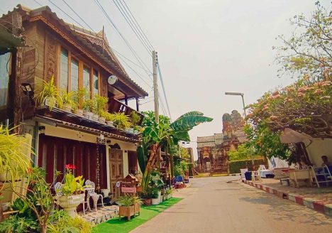 A charming boutique hotel surrounded by plants on a quaint Thai street.