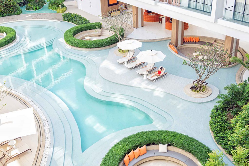 Overhead view of a resort pool with a woman lounging beside it.