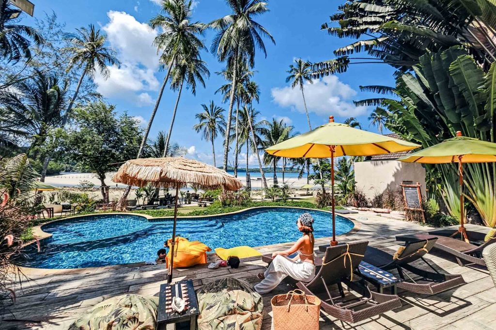 A pool at a resort with a woman relaxing beside it.