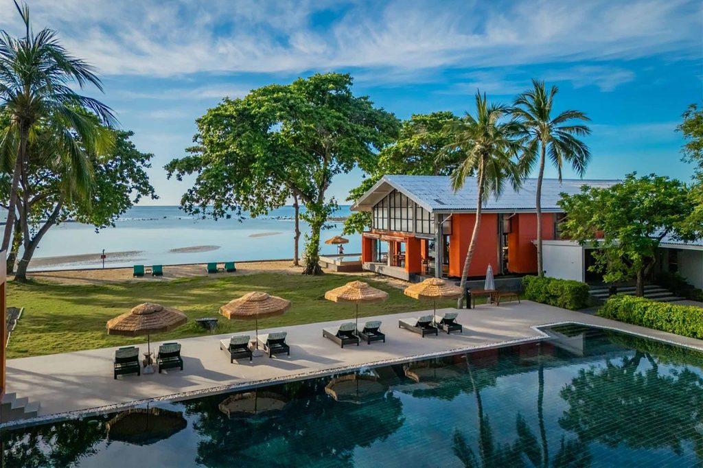 Resort pool with sun loungers and palm trees.