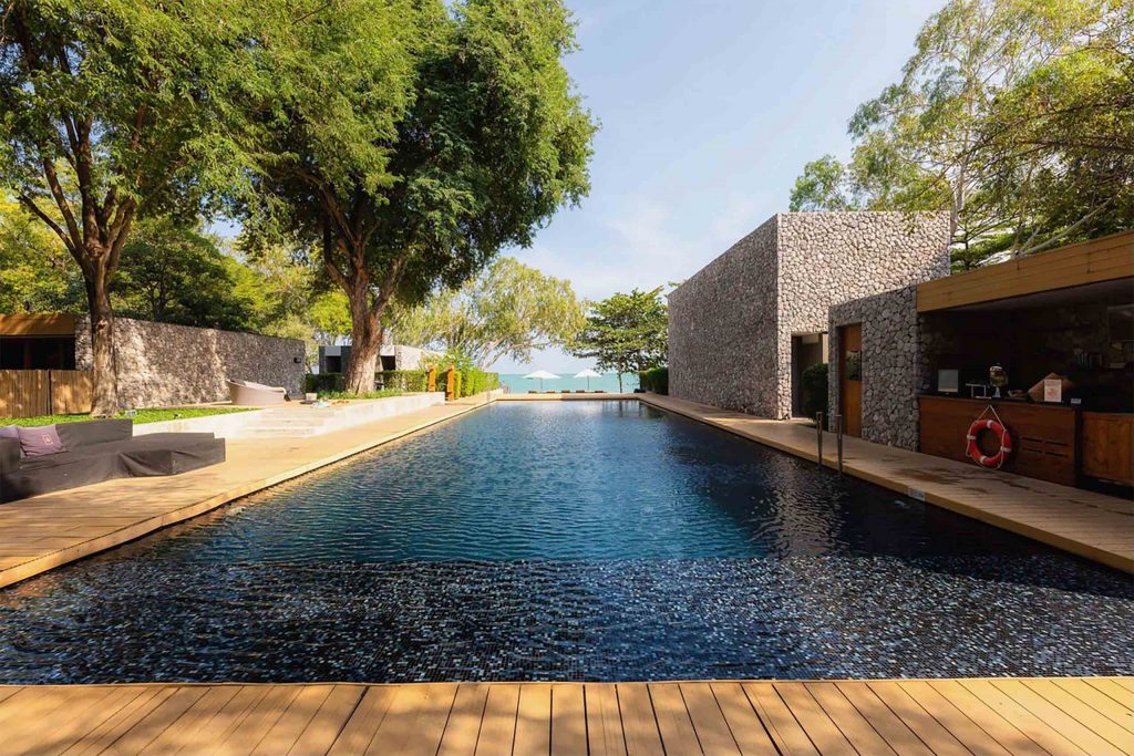 Long resort pool beside a brutalist building.