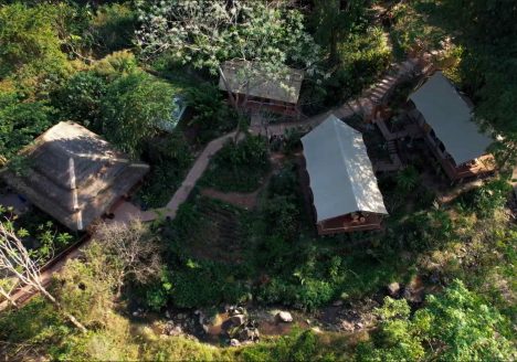 Overhead shot of several lodges surrounded by forest.