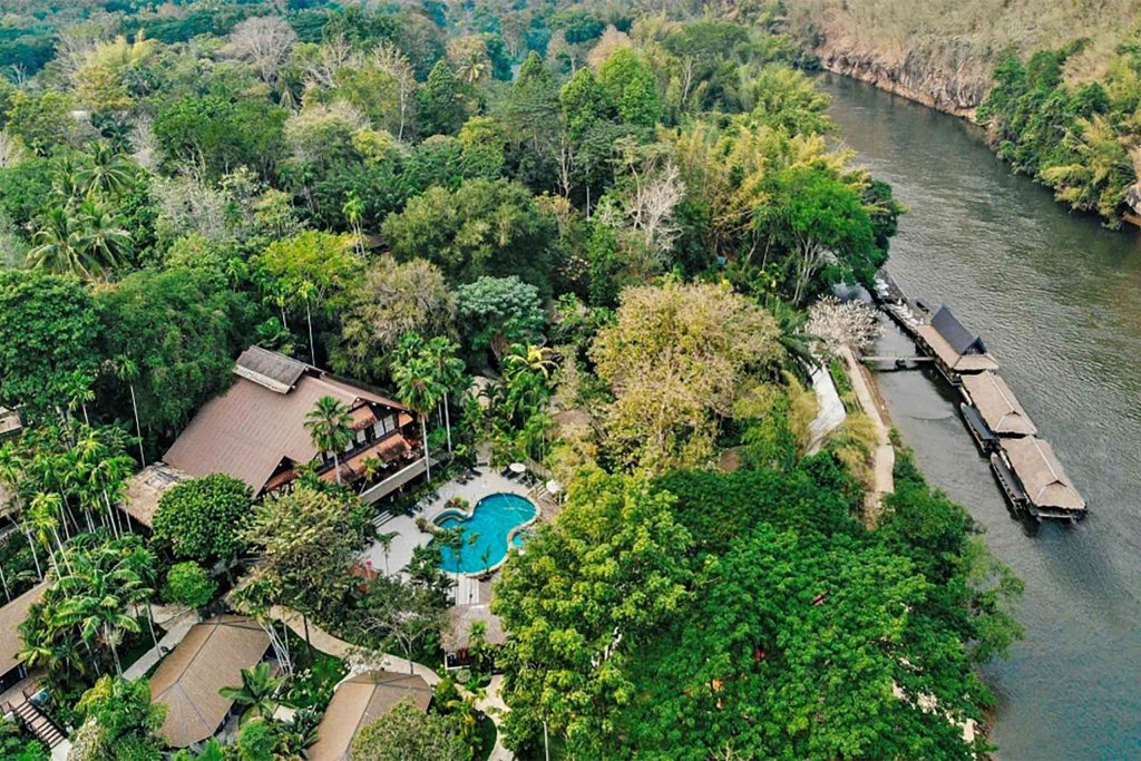 Overhead shot of a quaint resort by a river, surrounded by forest.