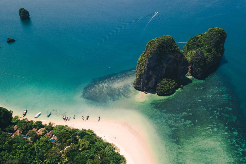 An aerial view of turquoise sea, white sand and dramatic limestone islands off Thailand's coast.