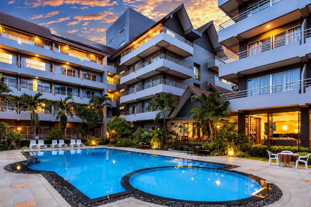 A classic modern resort with white walls surrounding a bright blue pool.